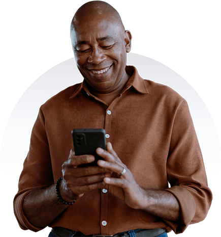 A smiling patient holds a phone and focuses intently on the screen.